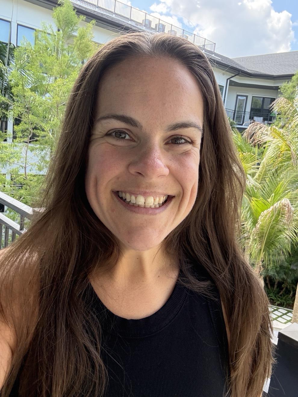 Portrait of Heather Looney smiling outdoors on a sunlit balcony in Sarasota, Florida
